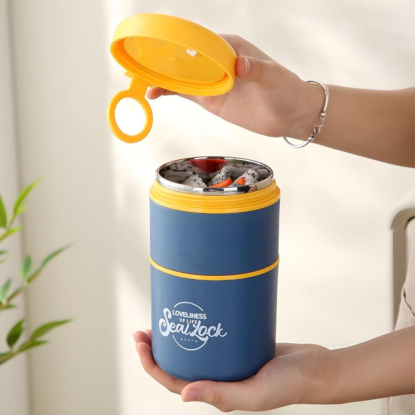 Miso station blue insulated bento food jar with yellow lid and carry loop held by hands, filled with dragon fruit.