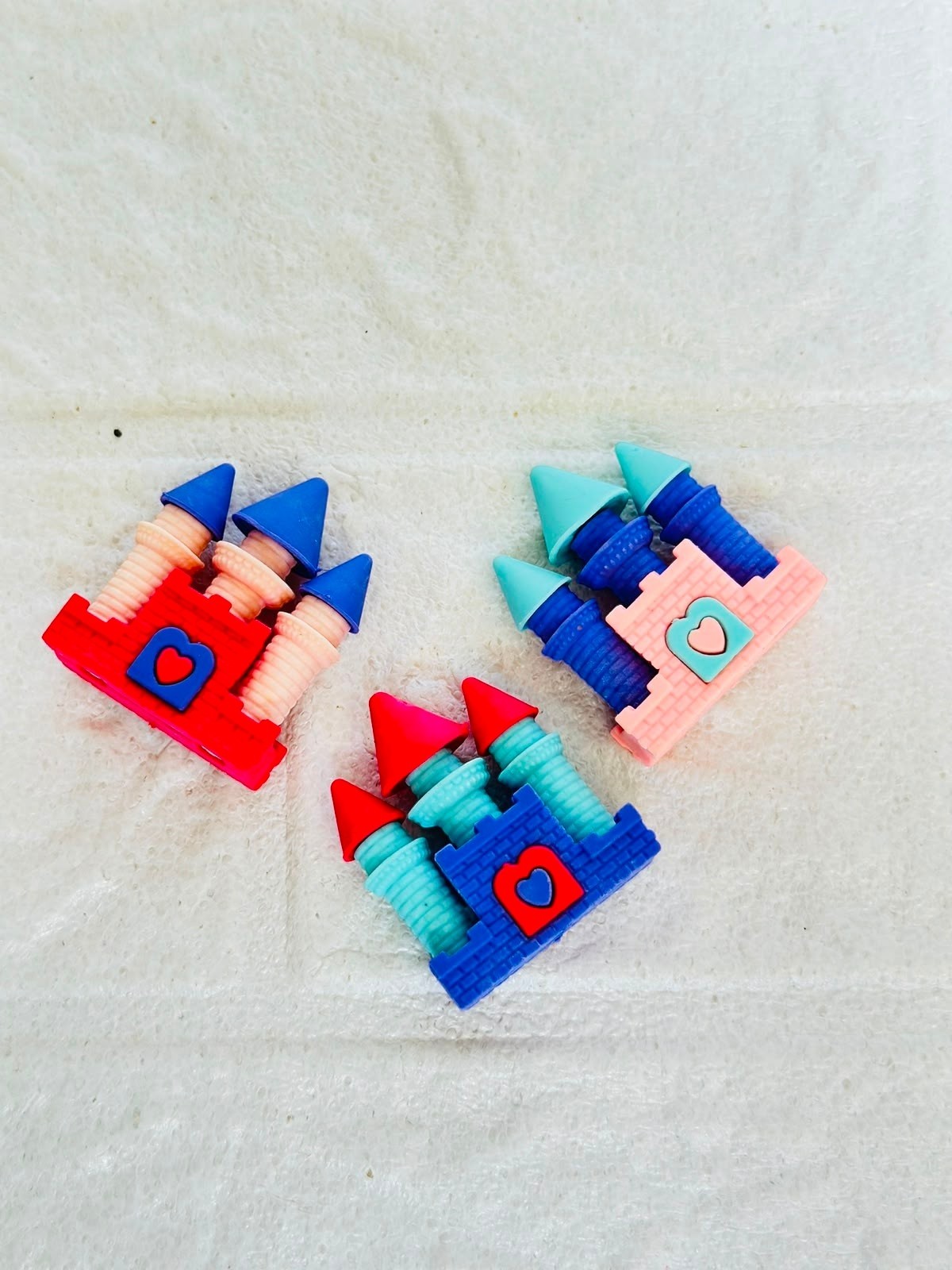 Miso station castle shaped erasers in red, pink, and blue with heart accents on a white textured background.