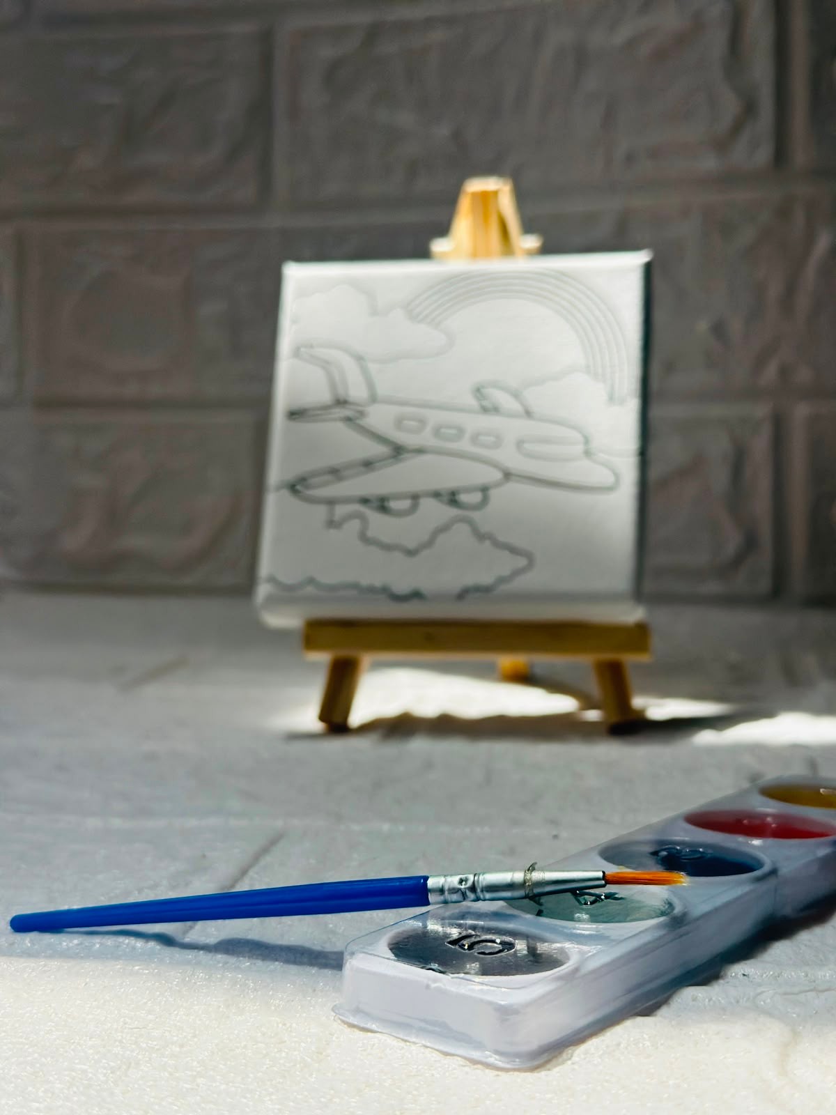 Miso station airplane painting kit with a pre-printed canvas on a wooden easel, paint palette, and brush.