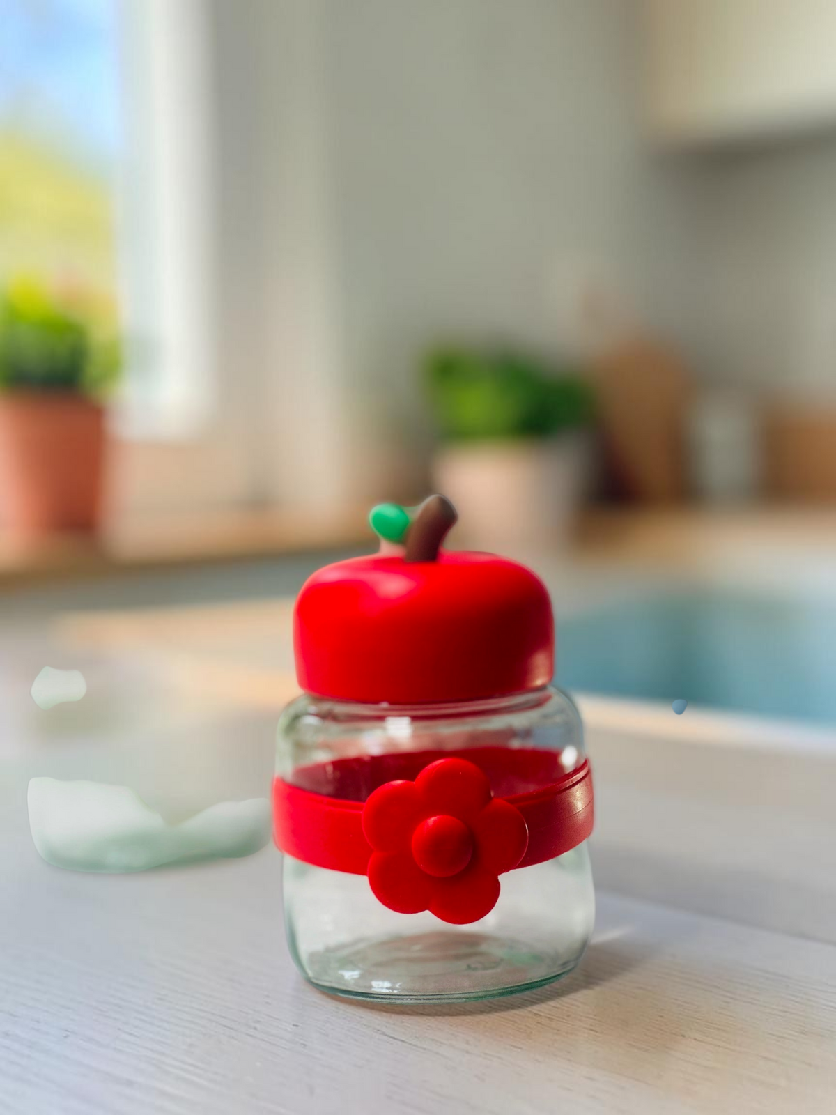 Miso station apple-shaped glass storage jars with colorful lids and flower-accented silicone bands on a white surface.