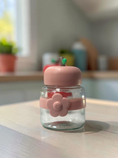 Miso station apple-shaped glass storage jars with colorful lids and silicone flower bands on a white surface.