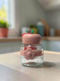 Miso station apple-shaped glass storage jars with colorful lids and silicone flower bands on a white surface.
