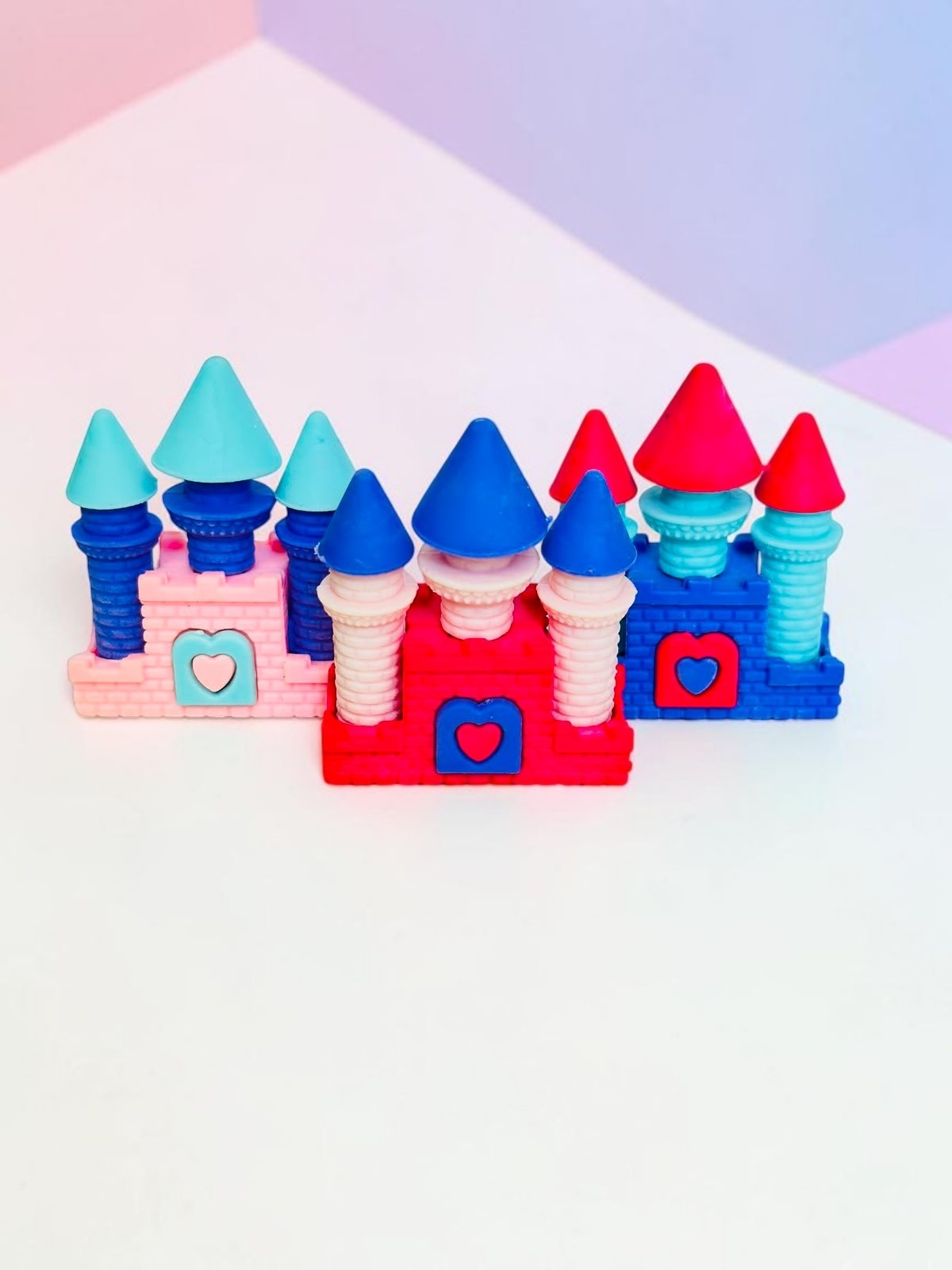 Miso station castle shaped erasers in pink, red, and blue with heart accents on a white textured background.