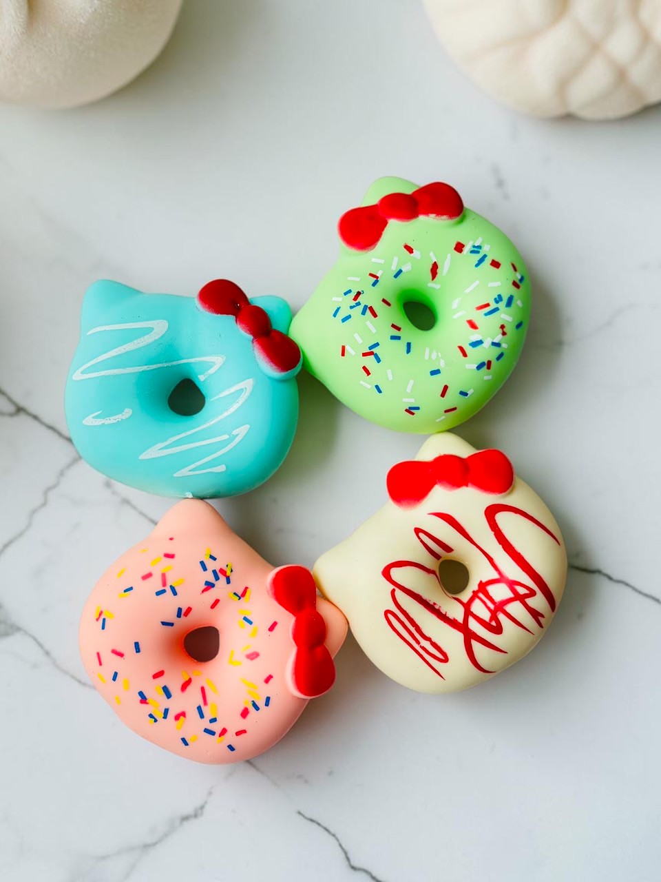 Miso station cat ear donut stress relief toys in blue, green, pink, and cream with red bows on a marble surface