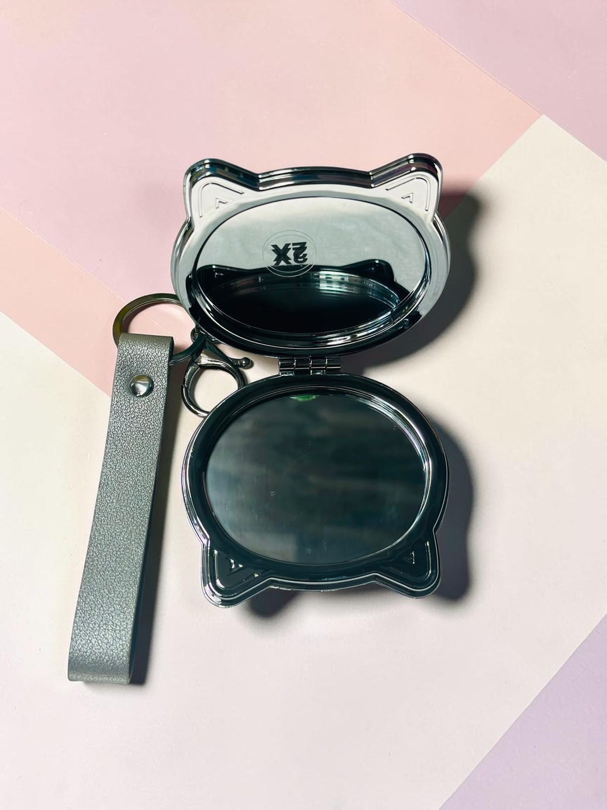 Miso station cat shaped silver metallic compact mirror with a keychain and wrist strap, open to show dual mirrors.