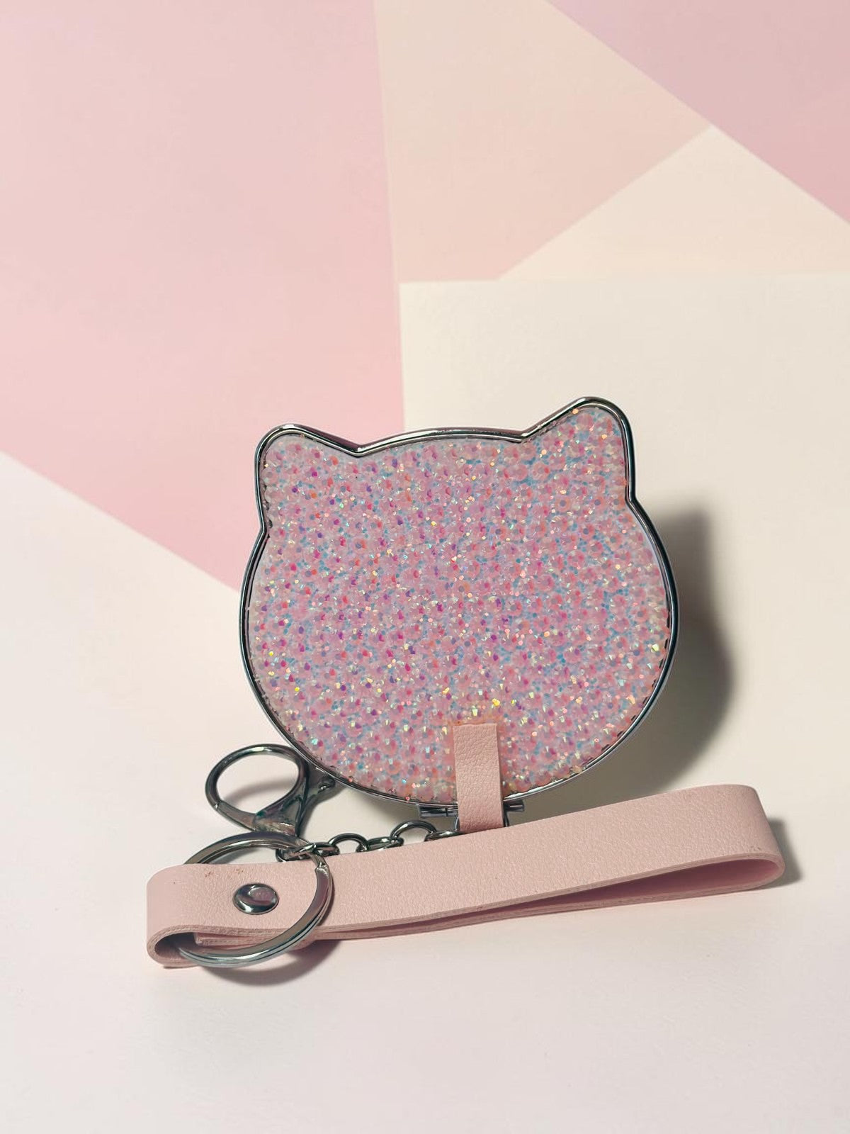Miso station cat-shaped compact mirror with a pink glitter finish, metallic edge, and a matching pink wrist strap.