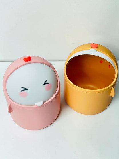 Miso station cute character desktop waste bins in pink and yellow with swing-top lids on a white brick background.