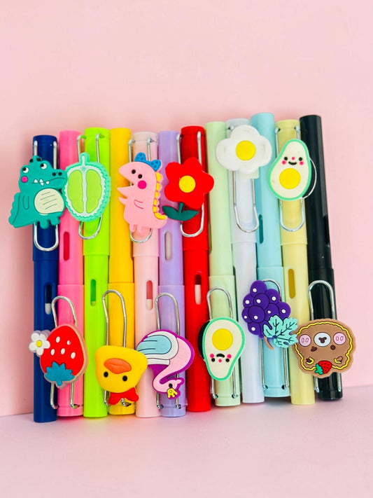 Miso station colorful gel pens with 3D silicone animal and food charms like dinosaurs, ducks, and fruit on a pink background