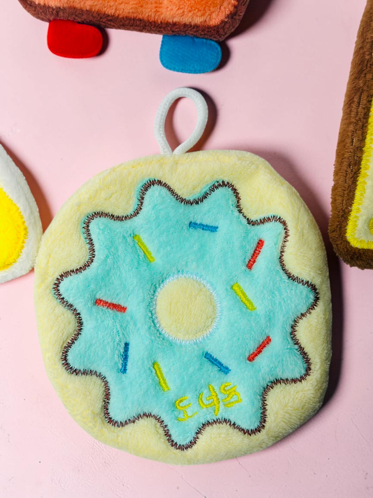 Miso station donut shaped kitchen sponge with blue icing, colorful sprinkles, and a white hanging loop