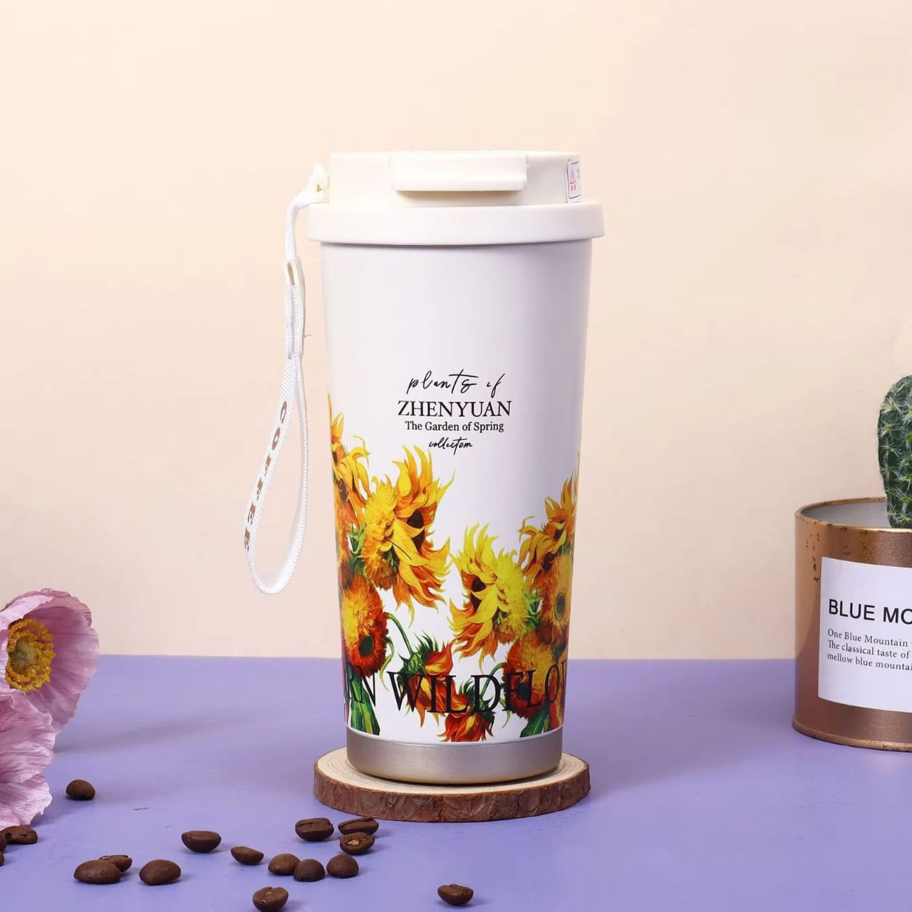 Miso station insulated travel tumbler with sunflower floral print, white lid, and carrying strap on a wooden coaster.