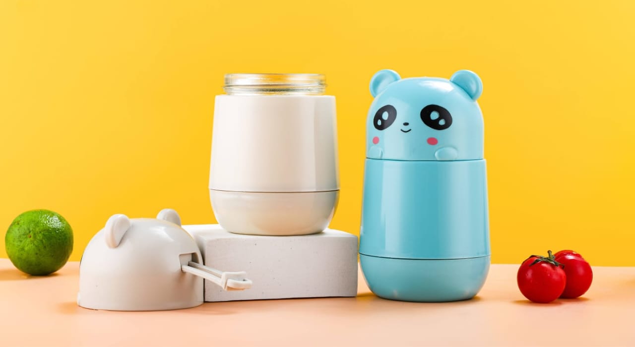 Miso station portable panda-themed manual food processor in blue and white on a yellow background with fresh produce.