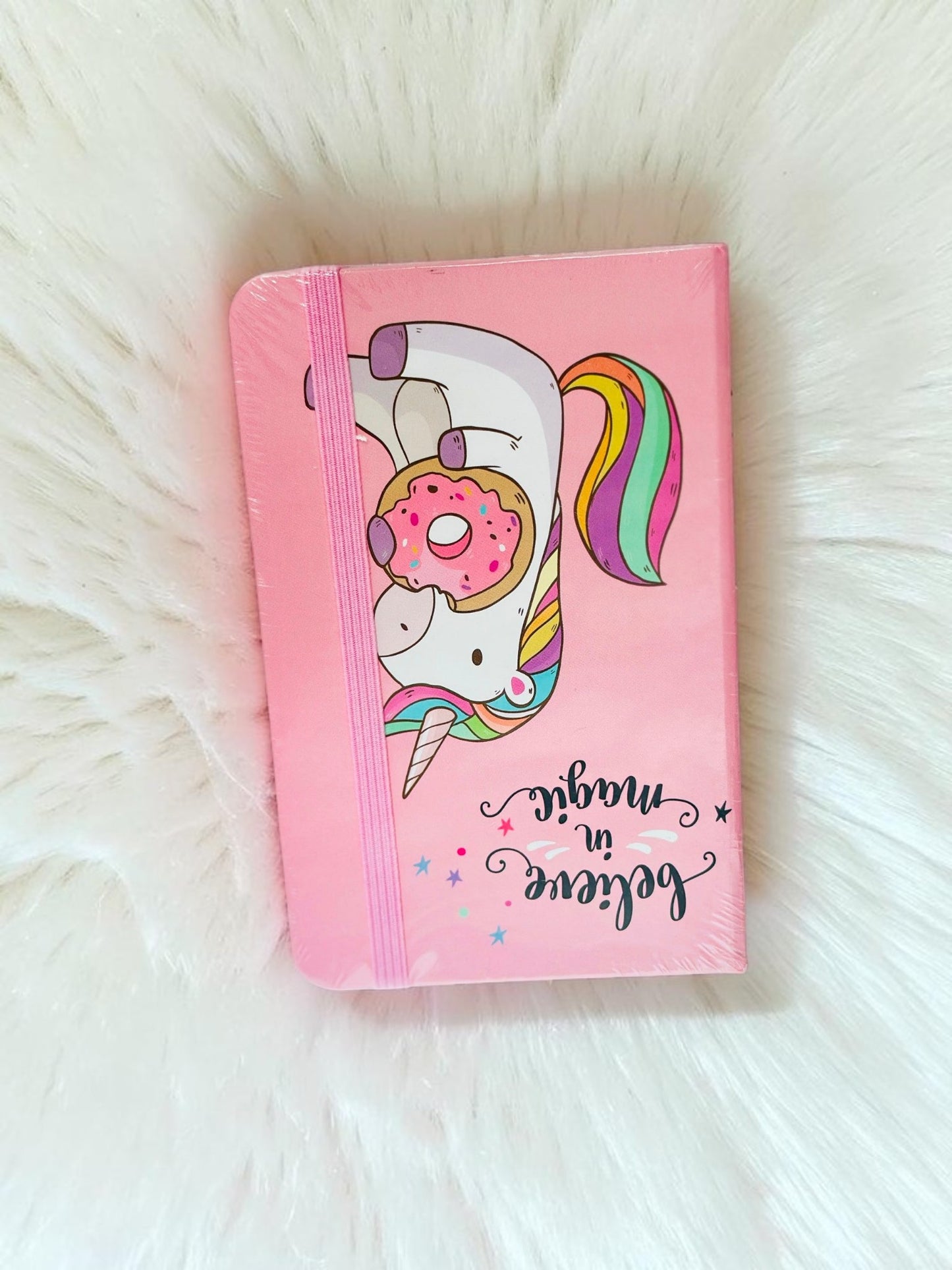 Miso station pink unicorn journal with a donut illustration, rainbow mane, and elastic band closure.