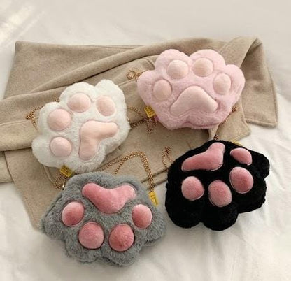 Miso station plush cat paw crossbody bags in white, pink, grey, and black with gold chain straps.