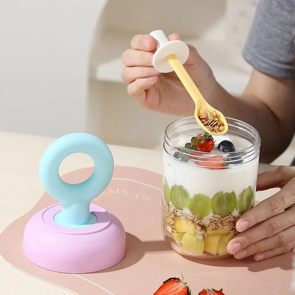 Miso station portable yogurt cup with clear body, pastel lid, and integrated spoon holding granola and fruit layers