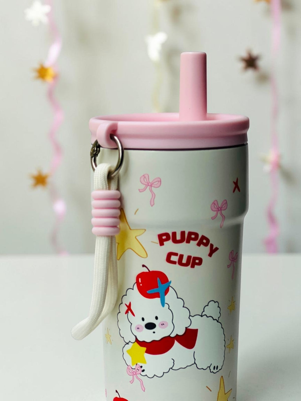 Miso station cream stainless steel tumbler with puppy illustration, pink lid, straw, and carrying strap.