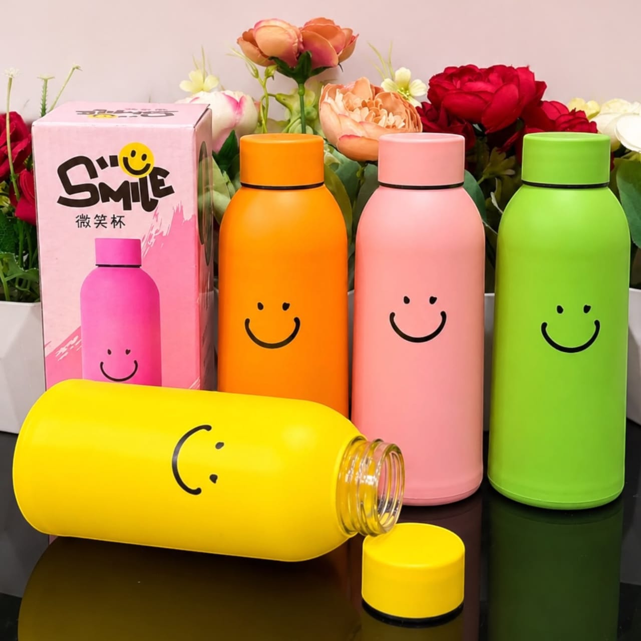 Miso station insulated water bottles in yellow, orange, pink, and green with a cheerful smiley face design.