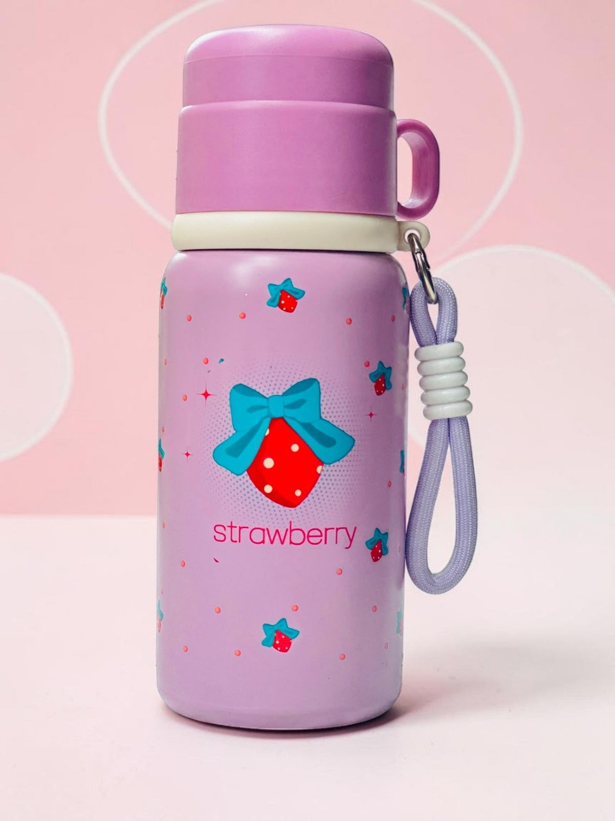 Miso station insulated stainless steel water bottle in pastel purple with strawberry and blue bow pattern and strap.
