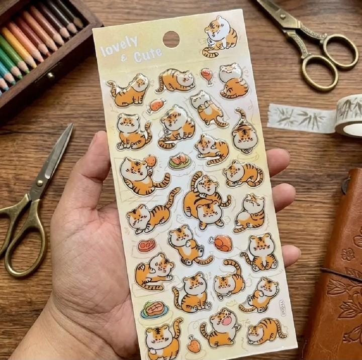 Miso station sticker sheet featuring cute orange tiger illustrations in various playful poses on a wooden desk