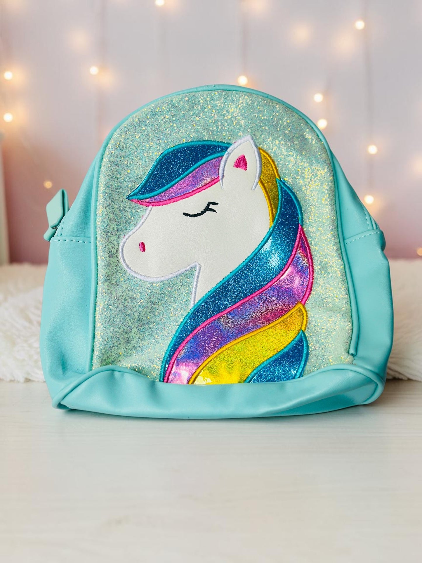 Miso station children's mini backpack in pastel blue with a glittery unicorn appliqué and multi-colored mane.