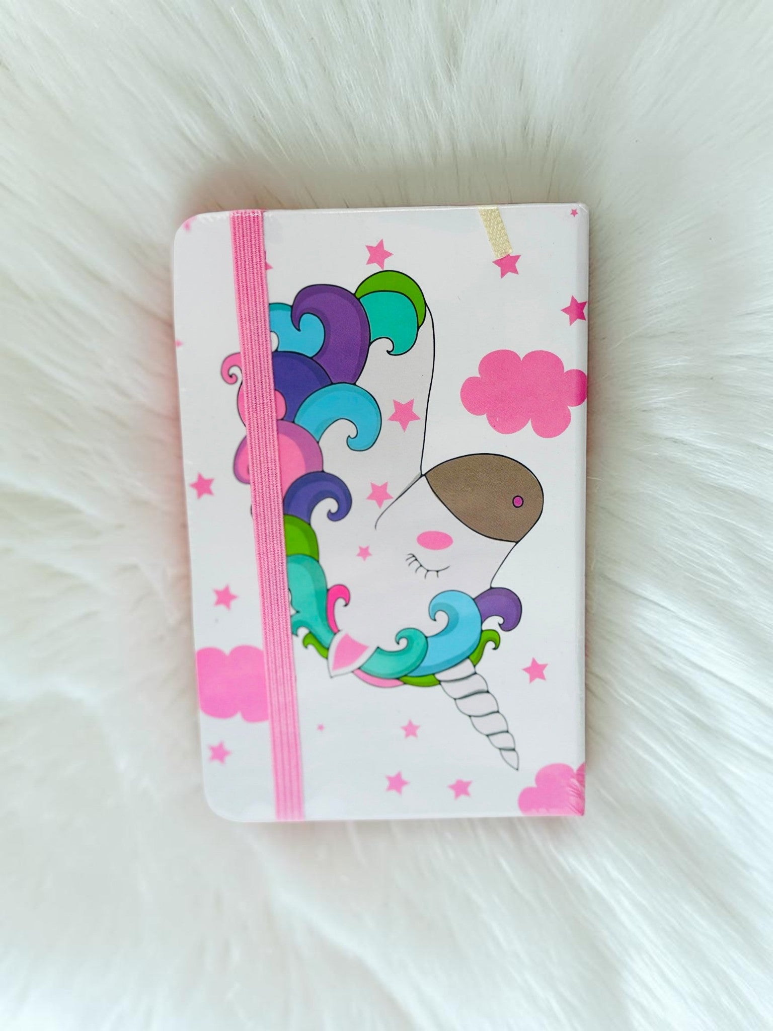 Miso station unicorn themed journal with a white cover, colorful mane illustration, and pink elastic band closure.