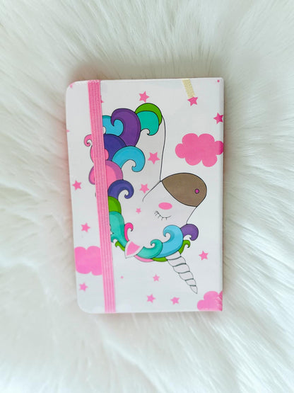 Miso station unicorn themed journal with a white cover, colorful mane illustration, and pink elastic band closure.