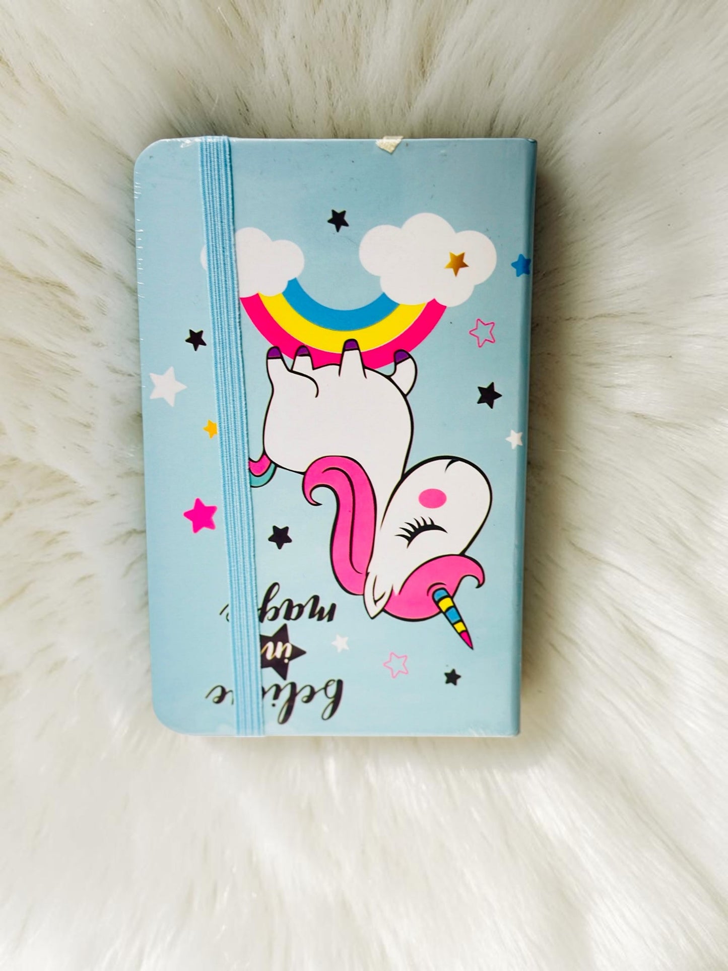 Miso station unicorn journal with a light blue cover, rainbow illustration, and secure elastic band closure.