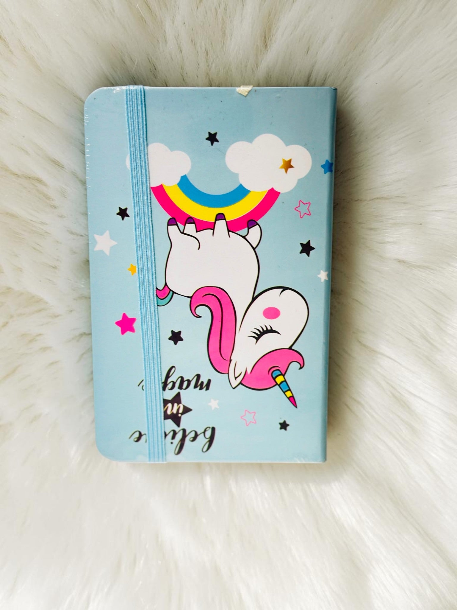 Miso station unicorn journal with a light blue cover, rainbow illustration, and secure elastic band closure.