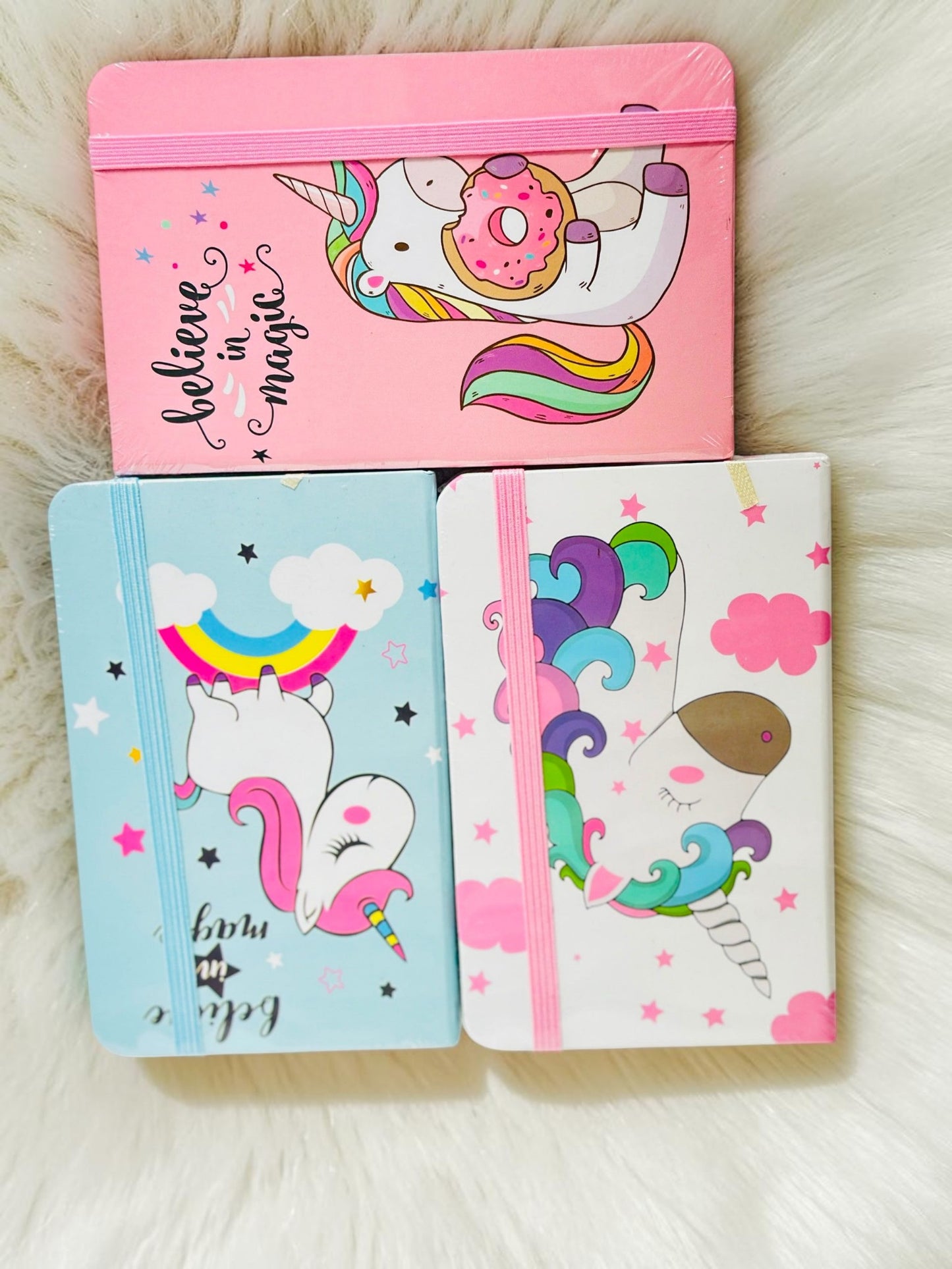 Miso station unicorn journals with elastic closures in pink, blue, and white featuring playful magical illustrations.