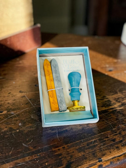 Miso station wax seal stamp kit with a light blue handle, gold base, and gold and silver wax sticks in a gift box.